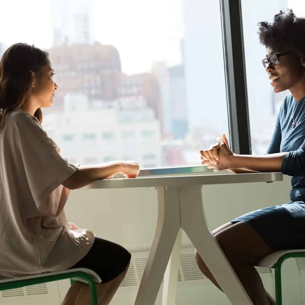 Deux femmes discutent lors d'une réunion dans un bureau lumineux.
